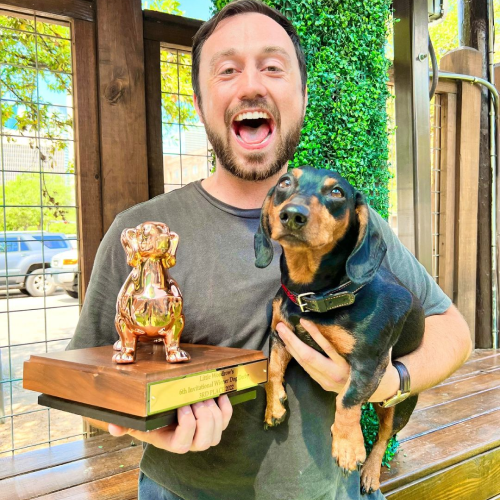 winner of wiener dog races holding trophy and daschund